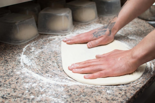 Dough for the pizza man's hand in the kitchen