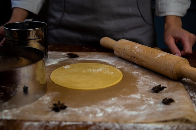 The dough rolled out and cut into a circle lies on the table on parchment sprinkled with flour next ...