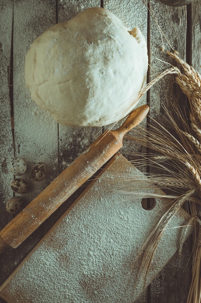 Фото Скалка для теста и колосья пшеницы на старом деревянном фоне, посыпанные мукой