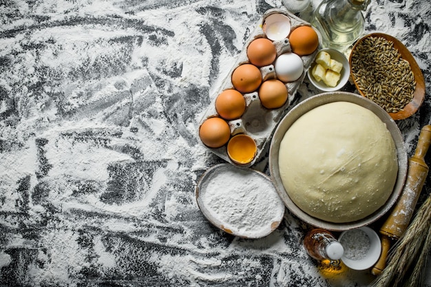 Dough with eggs butter and grain in bowls