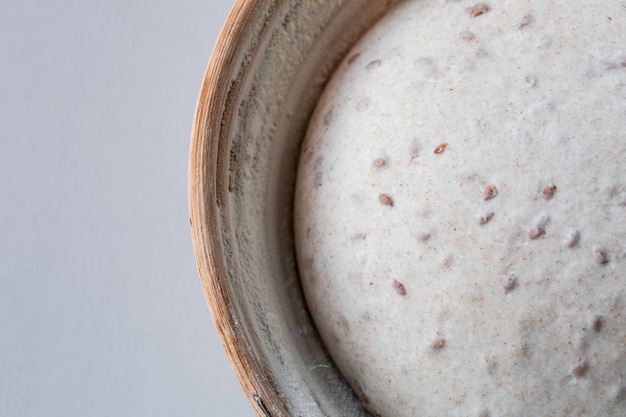 Dough with natural leaven with flax seeds in a rattan basket.