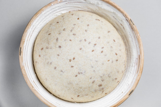 Dough with natural leaven with flax seeds in a rattan basket.