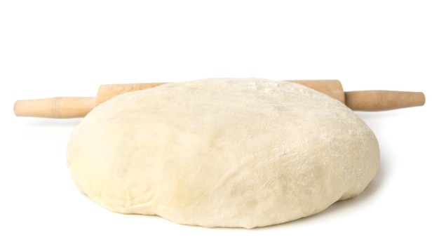 Dough and wooden rolling pin on white, close-up.