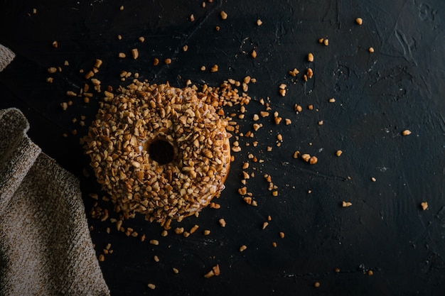 Doughnut  covered with nuts on dark surface