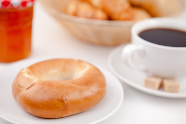 Ciambella e una tazza di caffè su piatti bianchi con zucchero e latte