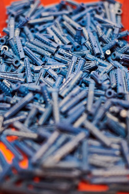 Dowels wall plugs close up. plastic blue dowels on red\
background, dowels for fixation and installation and various wall\
materials, concrete and wood. accessories for repairing and\
handymen