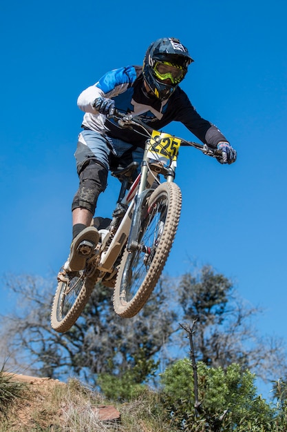 Photo downhill competition, biker jumps fast in the countryside.