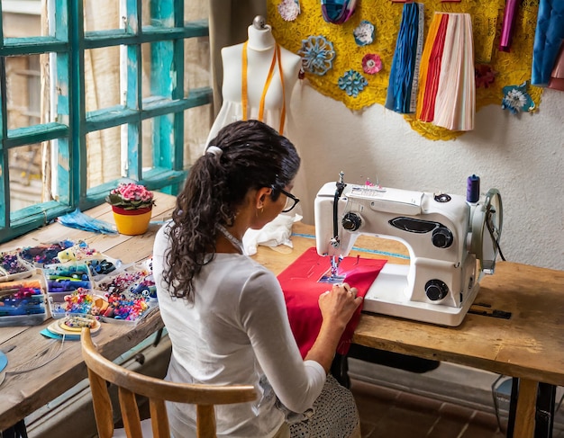 Downward view of a female fashion designer at a sewing machine back focused on crafting intricate de...