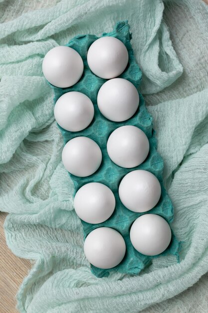 A dozen white eggs on a green towel.