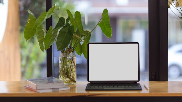Foto draagbare tablet in leeg schermmodel voor montage op houten tafel over onscherpe achtergrond
