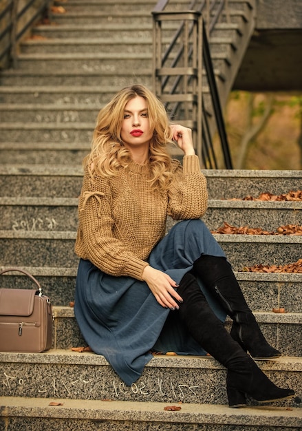 Draagbare trends Laag oversized gebreid over girly rok Herfst outfit formule Stijl Trui en rok Combo voor herfst Vrouw prachtig kapsel zit buiten op trappen Warme herfst Herfst modetrend