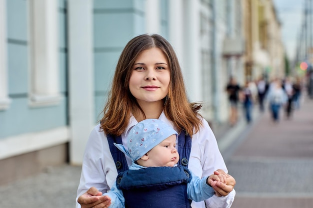 Draagdoek met baby wordt vastgehouden door vrouw op straat