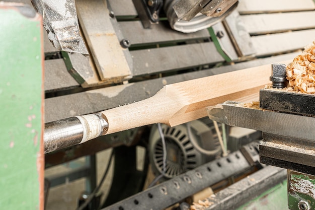 Draaibank met gereedschap dat houten stuk verwerkt terwijl de vorm symmetrisch rond de as in schrijnwerk wordt gesneden