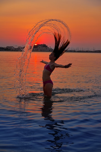 Draaiende het haarflits van het meisje bij zonsondergangstrand