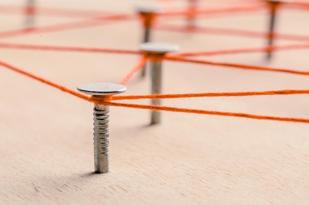 Draden en spijkers op een houten plank