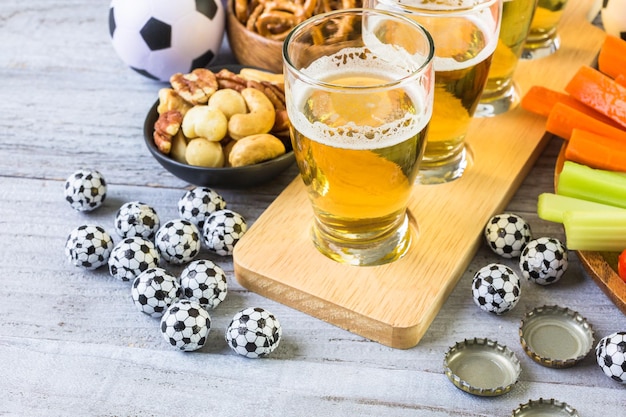 Photo draft beer and salty snacks on the table for soccer party.