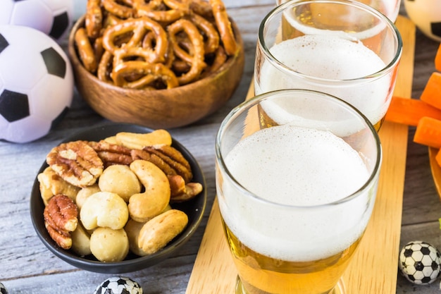 Draft beer and salty snacks on the table for soccer party.