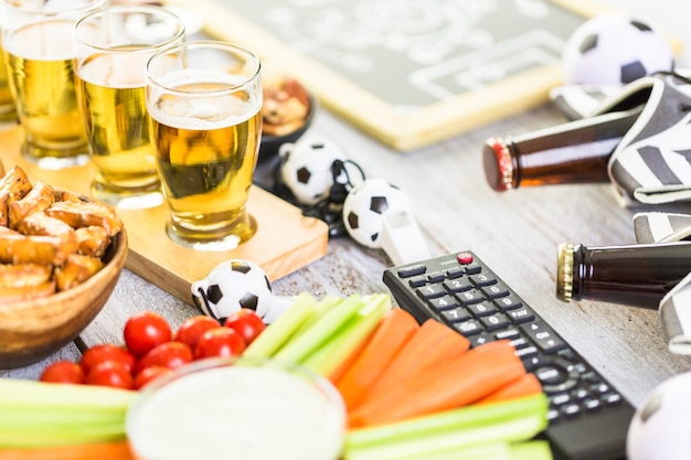 Draft beer and salty snacks on the table for soccer party.