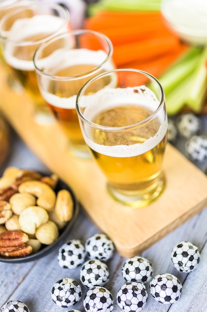 Разливное пиво и соленые закуски на столе для футбольной вечеринки.