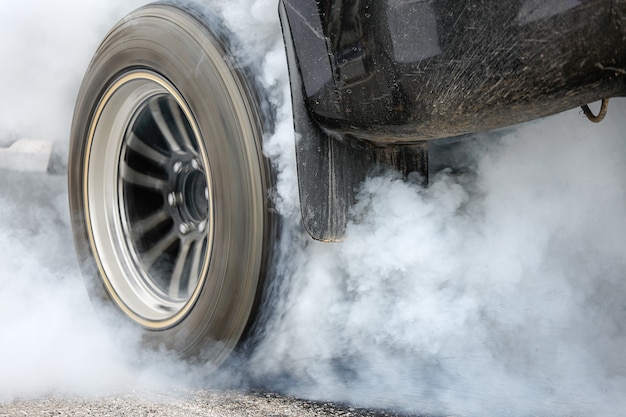 Photo drag racing car burns rubber off its tires in preparation for the race