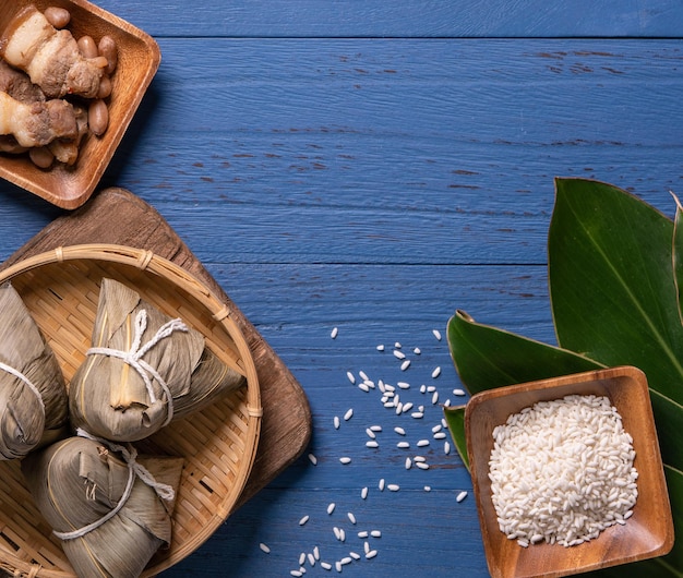 Dragon boat festival concept rice dumpling zongzi traditional\
chinese food on blue wooden background for duanwu festival top view\
flat lay design concept