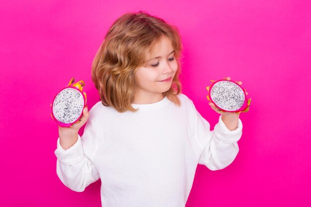 Dragon fruit Kid met draken fruit in studio Studio portret van schattig kind met draken vrucht geïsoleerd op gele achtergrond kopieerruimte