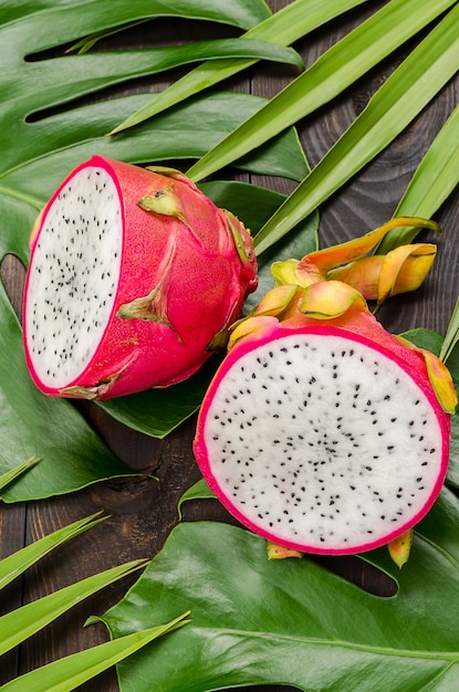 Dragon fruit on the leaves of palm and monster. 