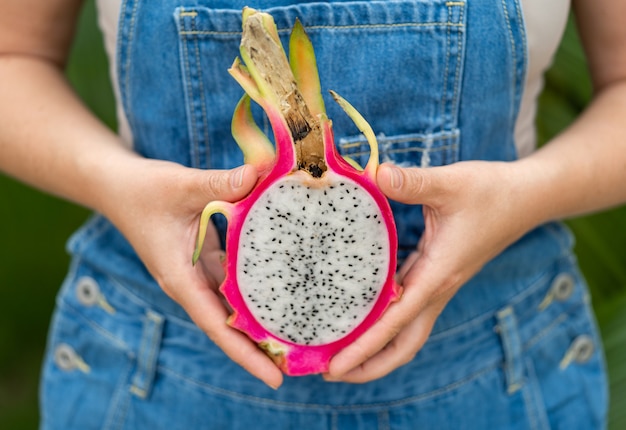 Foto dragon fruit pitahaya nelle mani delle donne in tuta di jeans.