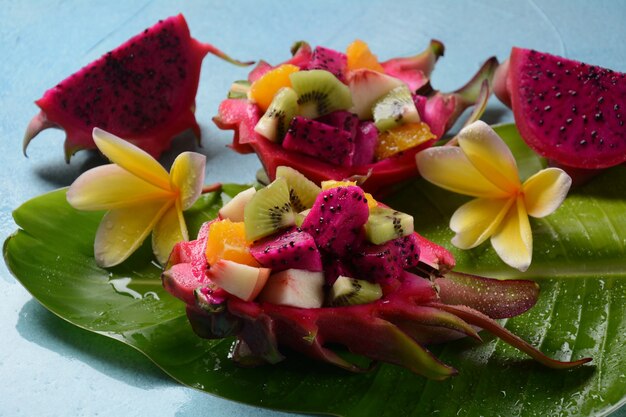 Dragon fruit (Pitaya, Pitahaya). Gesneden stukjes pitahaya fruit en fruitsalade, en frangipani bloemen.