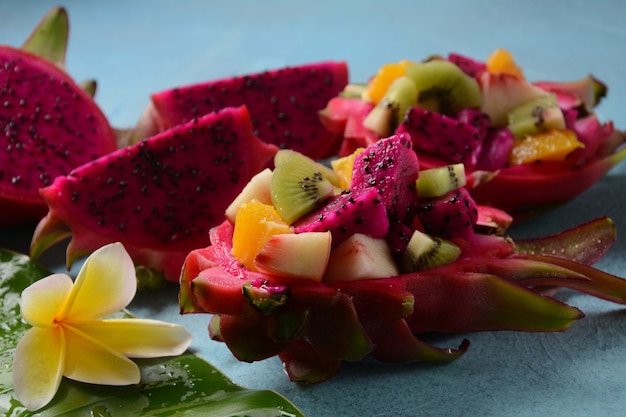 Dragon fruit (Pitaya, Pitahaya). Gesneden stukjes pitahaya fruit en fruitsalade, en frangipani bloemen.