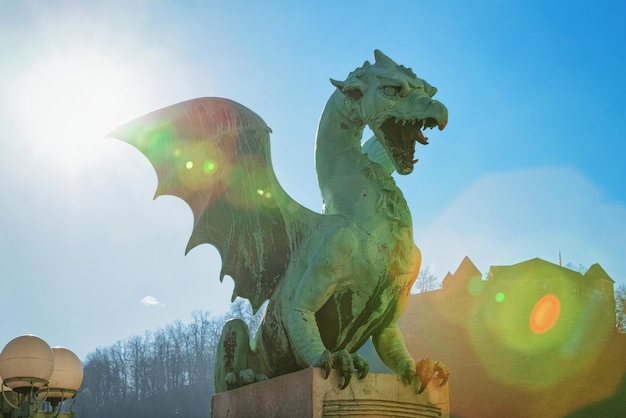 スロベニアのリュブリャナ旧市街の通りにある竜の像。美しいスロベニアの街の彫刻、青い空と背景の城の眺め。都市の緑の首都のシンボル。翼を持つ動物の置物の頭。