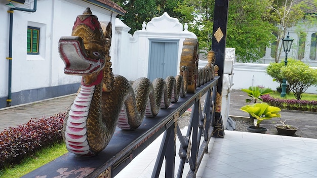 A dragon statue sits on a railing outside a temple.