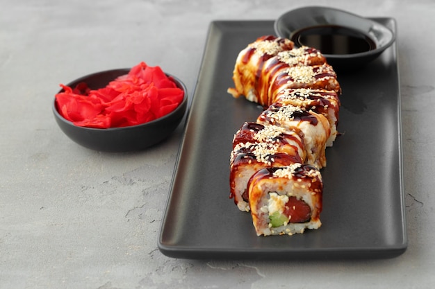 Foto dragon sushi roll met paling op zwarte keramische plaat close-up