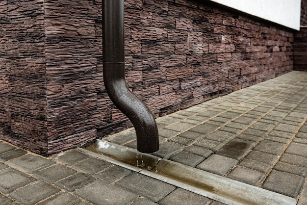 写真 茶色のレンガの壁の排水管。縦樋。
