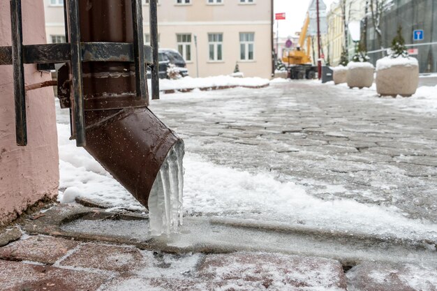 Водосточные трубы покрыты льдом и снегом После сильной метели город покрыт снегом и льдом На фасаде здания много сосулек Лед на тротуарах и дорогах