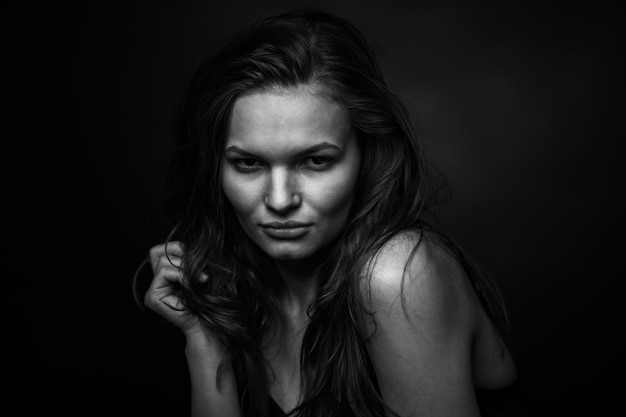 Dramatic black and white portrait of a beautiful girl on a dark background