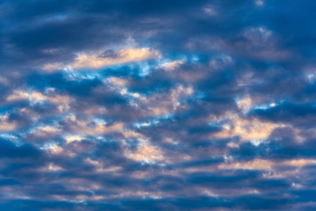 Nuvole drammatiche nel cielo azzurro illuminate dai raggi del sole al tramonto per cambiare il tempo estivo