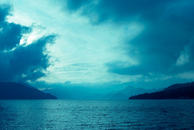 황혼에 의해 일본의 산 호수 위의 극적인 구름