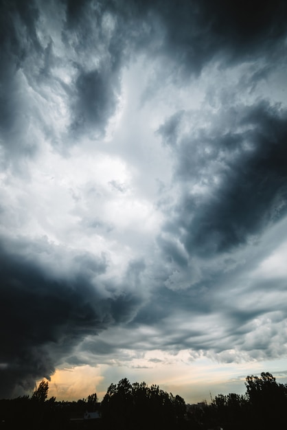 극적인 cloudscape. 비가 내리기 전에 어두운 무거운 뇌우 구름을 통해 맑은 빛. 흐린 비오는 날씨. 폭풍우 경고 폭풍우 흐린 하늘에 햇빛입니다.