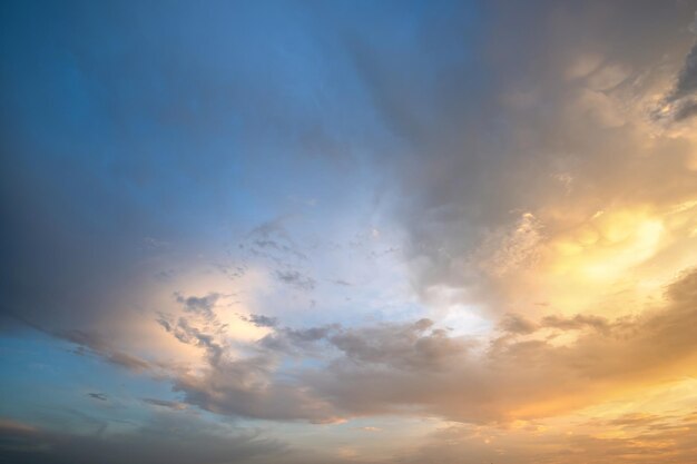 オレンジ色の夕日と青い空に照らされたふくらんでいる雲と劇的な曇りの日没の風景