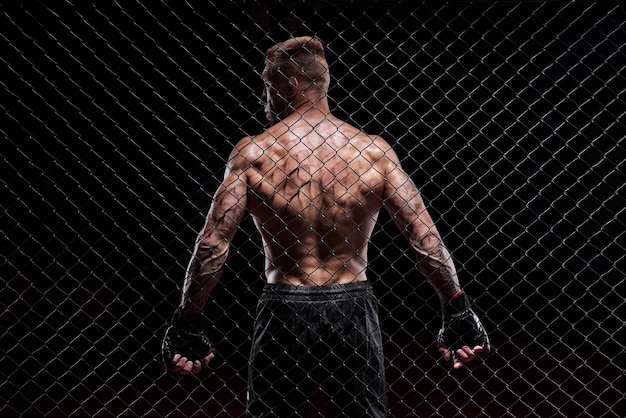 Dramatic depiction of a fighter in an octagon cage Back view The concept of sports Muay Thai martial arts