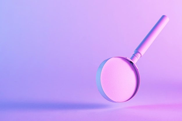 Dramatic duotone image of a floating magnifying glass over a pink through blue graduated background