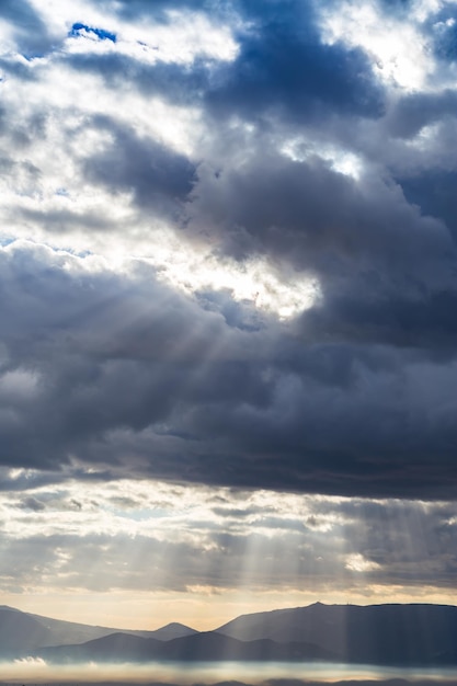 Dramatic heavy clouds above the landscape with sunrays coming through