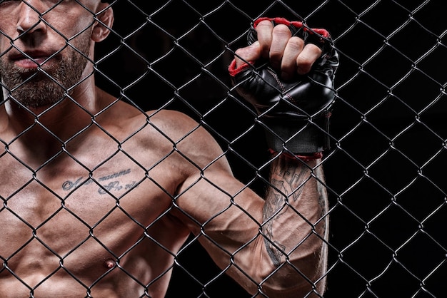 Immagine drammatica di un combattente di arti marziali miste in piedi in una gabbia ottagonale il concetto di arti marziali di pugilato sportivo
