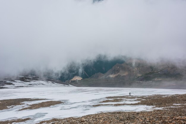 雑多な山の谷の上の雲の中の人々 との劇的な風景 多色の谷の上の雲の中の観光客 雪の石の丘の上の低い雲 低い雲の中の素晴らしい高山の風景