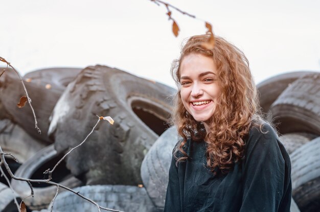 Dramatic photo of a cheerful girl at a tire repair dump Waste disposal