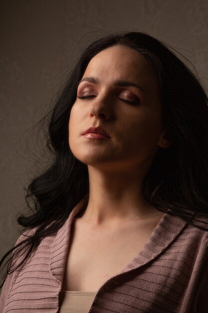 Dramatic portrait of awesome woman with long hair and closed eyes posing in the shadow