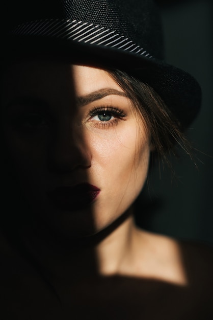 Dramatic portrait of sexy young girl in black hat with red lipstick