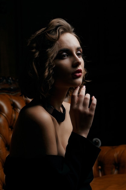 Dramatic portrait of thoughtful brunette girl at studio with shadows. Low key shot