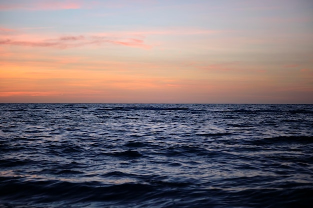 日没時の劇的な赤い海の波と、柔らかい夜の海の暗い水